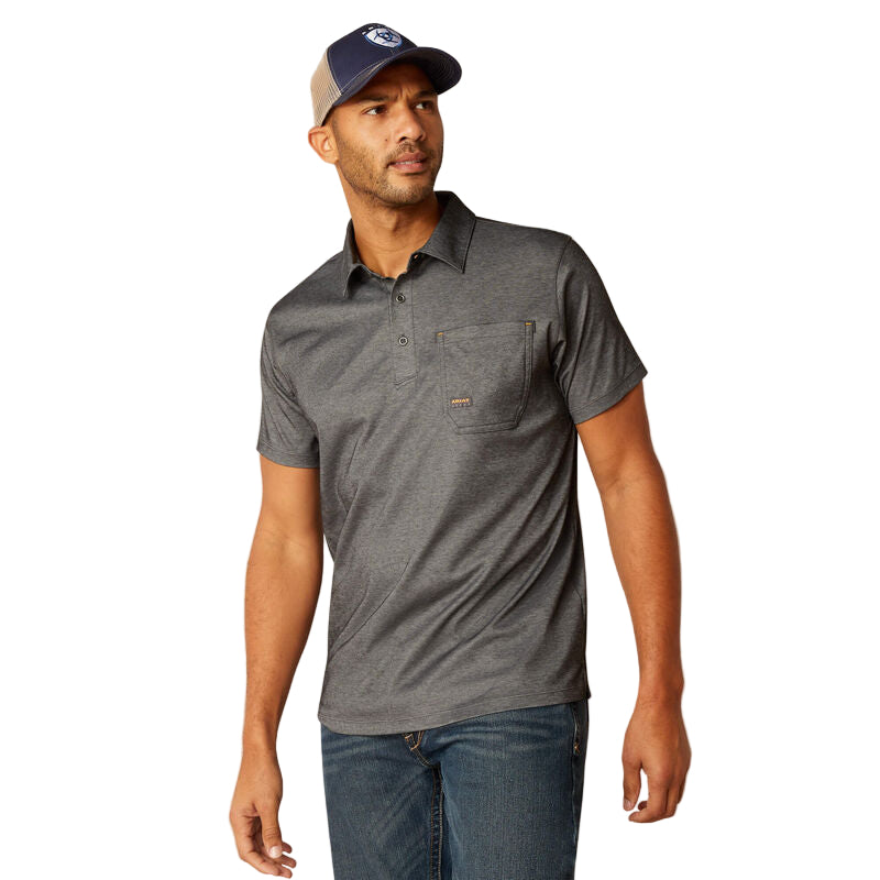 A man wearing a charcoal Rebar Foreman Polo with a reinforced chest pocket and metal buttons, paired with jeans and a cap.